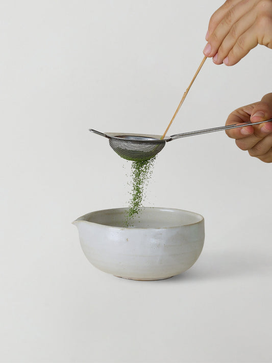 Sifting green tea into ceramic bowl
