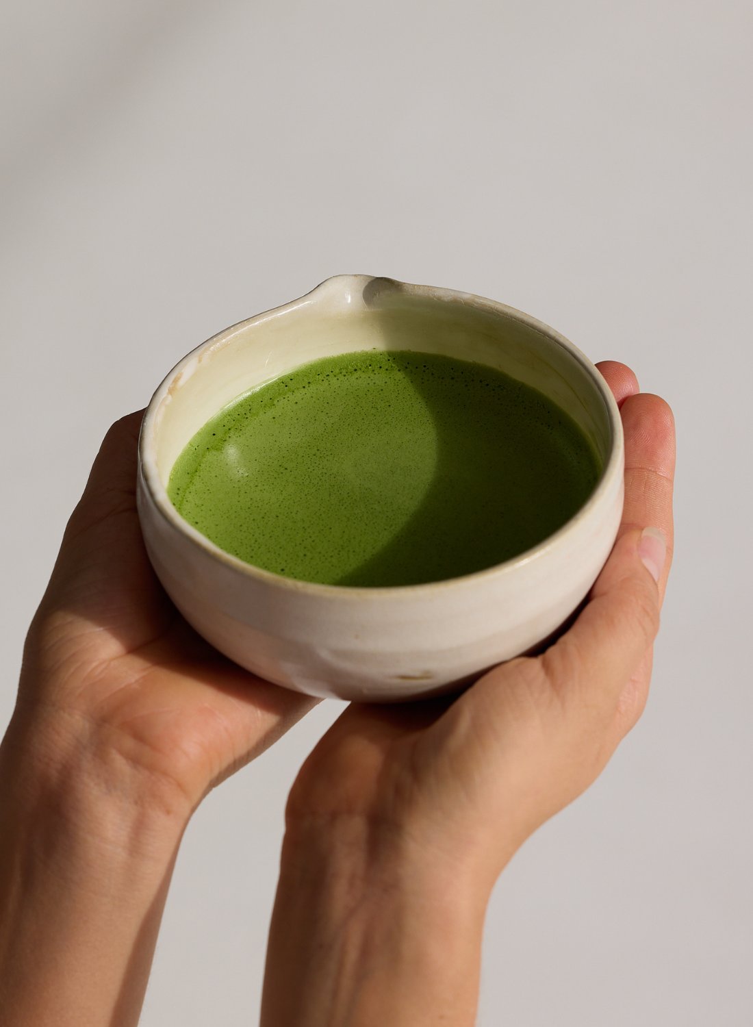 Hands holding matcha tea bowl 